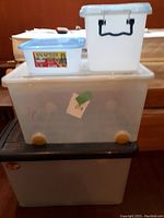 Stack of four clear storage boxes showing sizes, lids, and details such as handles and wheels.