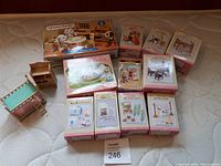 Overview of all Sylvanian Families dollhouse furniture and accessories with boxes in Japanese text, displayed on mattress surface.