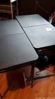 Two black folding tables set up side by side showing rectangular tops and metal legs.