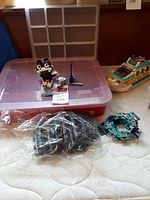 Photo showing the large red plastic LEGO sorter box with clear lid, small clear compartment sorter, LEGO cat and mouse models, LEGO boat set, and bags of LEGO pieces including train tracks.