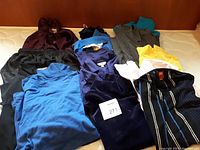 Full view of assorted clothing laid out showing tops and pants in various colors and styles.
