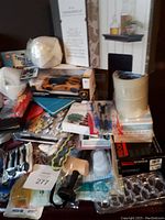 Lot of assorted new household and miscellaneous items including light bulbs, puzzles, tapes, rubber mallet, toy car, pens, and disposable products.