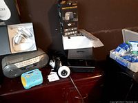Sony stereo boombox, white headphones box, Brother label maker, and VuPoint Digital Film & Slide Converter on table