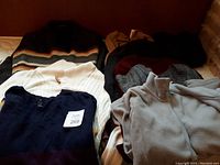 Photo showing a variety of winter sweaters and a gray wool jacket with multicolor stripes.