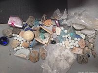 Top view showing assortment of polished and rough stones, beads, and geode slices scattered on surface.
