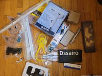 Overview photo of lot showing Conair hair dryer in box, yellow plastic tool, folding rulers, black pouch, and small wooden box with map design