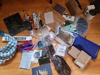 Lot of miscellaneous general merchandise including personal care and accessories spread on wooden floor.