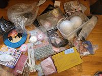 Full overview of various items in the lot including DIY craft kits, face mask, colorful fabrics, spherical objects, and other miscellaneous pieces packed together.