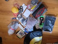 Photo showing wide view of assorted items on floor, including tire cover and various automotive parts and household items