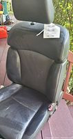 Single photo showing black leather Acura car seat with headrest and seatbelt buckle.