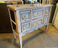 Front side view of rustic wood framed six drawer buffet showing distressed finish and glass knobs on drawers.