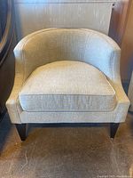 Front view of the occasional chair showing light beige upholstery and cushioned seat