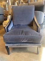 Front view of dark gray velvet upholstered armchair with wooden frame and feather/down cushion.