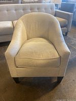 Front view of cream upholstered occasional chair, showing curved backrest and removable seat cushion.