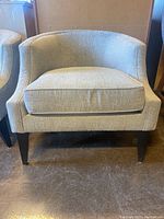 Front view of the light grey upholstered barrel-back occasional chair showing removable seat cushion