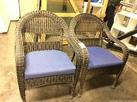 Pair of brown faux wicker chairs with blue cushions, front view
