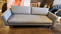 Front view of entire sofa on concrete floor showing cushions, arms and base