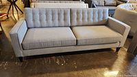 Front view of gray upholstered sofa showing overall appearance, tufted back and removable cushions