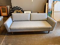 Front view of grey upholstered sofa showing seat cushion, back cushions and wood legs