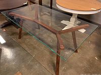 Perspective view showing clear glass top and angled wooden base