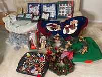 Wide view capturing all Christmas decorations including boxed ornaments, tree skirts, wreaths, Santa figurine, garland, and storage containers.