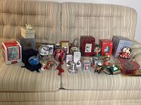 Wide angle showing full Christmas lot with all items arranged on couch, including snow globes, ornaments, figurines, candy dish, and boxed items