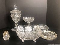 Overall lot showing three pinwheel patterned crystal pieces including tall lidded candy dish, small candy dish, square serving dish