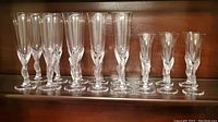 Front view of all 10 champagne flutes and 6 cordial glasses on shelf
