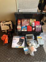 Overview of Rubbermaid toolbox with various drill bits, screws, and hardware arranged in and around it on floor