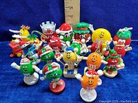 Group photo of 17 M&M's collectible toy figures arranged closely with a ruler behind them to show size.