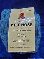 Close-up of tag on blue kilt hose showing brand Edgar of Scotland, composition 80% wool and 20% nylon, size large, care instructions, and origin UK