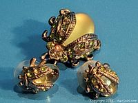 Front view of lady bug brooch and earrings showing glass body and green rhinestones on metal.