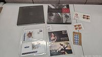 Overview of the entire stamp collection lot including two large books, assorted first day covers, loose stamps on and off the backing cards, and a card with Queen Elizabeth II.