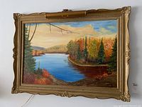 Front view of framed landscape oil painting with mounted brass light above the frame.