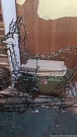 Lighted reindeer wire frame with string lights, positioned in front of two stacked plastic storage totes, one beige and one green.