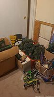 Boxed and loose Christmas decorations including faux greens, cords, and holiday cutouts in a basement room