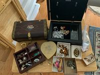Overview of multiple jewellery boxes and assorted costume jewellery pieces arranged on a wooden surface