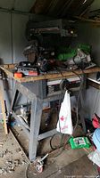 Craftsman radial saw mounted on metal stand with casters. Items and area show rust, dust and dirt accumulation.