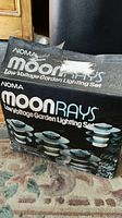 Box front showing NOMA Moonrays branding and product image with six green stake lights