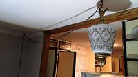 Photo of hanging swag lamp from a distance showing the full length of chain and lamp attached to ceiling and doorway.