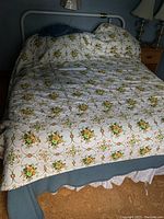 Photo of queen bed made up with floral bedding, mattress, and boxspring visible, showing bed setup and bedding pattern