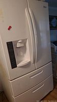 Front view of white LG French door refrigerator with water and ice dispenser on left door and two lower freezer drawers.