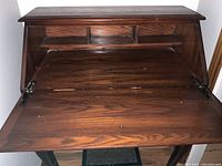 Front view of the secretary desk with drop-down front opened showing the writing surface and small cubby slots.