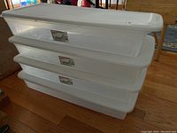 Four stacked Sterlite storage containers showing clear plastic sides and white lids.