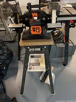 Front view of bench grinder mounted on metal stand with wooden top