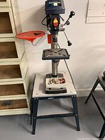 Front view of drill press on stand with sanding drum kit on base