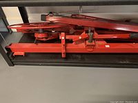 Collapsed hoist folded flat on shelf showing folded support arms and base