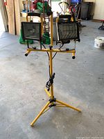 Front view of dual halogen lights on tripod stand showing handles and power cords.