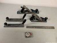 Photo of the three hand planers (various sizes) and two rasps laid out with tape measure for scale.