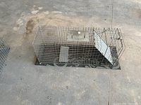 Top view of the large live animal trap showing metal wire mesh construction, spring door, and handle.